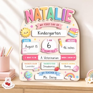 K&ouml;nnte beinhalten: Ein bogenf&ouml;rmiges Holzschild mit der Aufschrift NATALIE und Abschnitten f&uuml;r den ersten Kindergartentag, Datum 15. August, Alter 6 Jahre, Gr&ouml;&szlig;e 117 cm, Berufswunsch Tierarzt, Lieblingsfarbe Lavendel, Essen Erdbeeren, Tier Hase und Lehrerin Ms. Daisy.