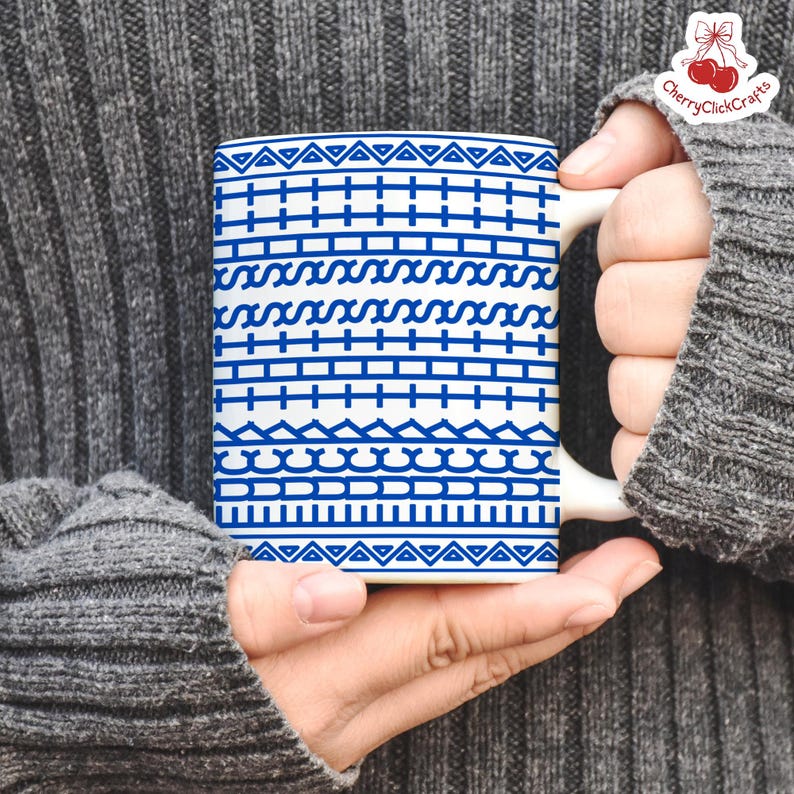 Puede incluir: Taza de cer&aacute;mica blanca con un patr&oacute;n geom&eacute;trico azul. El dise&ntilde;o presenta filas de tri&aacute;ngulos, l&iacute;neas y formas onduladas. La taza es sostenida por una persona que lleva un su&eacute;ter gris.
