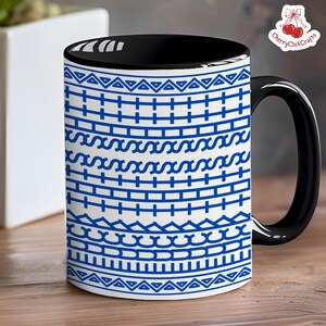 Puede incluir: Una taza de caf&eacute; de cer&aacute;mica con asa e interior negros. El exterior presenta un fondo blanco con un patr&oacute;n geom&eacute;trico azul repetido. La taza est&aacute; sobre una superficie de madera.