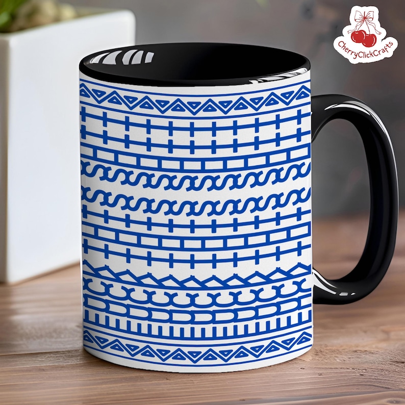 Puede incluir: Una taza de caf&eacute; de cer&aacute;mica con asa e interior negros. El exterior presenta un fondo blanco con un patr&oacute;n geom&eacute;trico azul repetido. La taza est&aacute; sobre una superficie de madera.