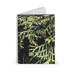 May include: A spiral-bound notebook featuring a vibrant, stylized image of evergreen foliage. The cover showcases a close-up of green and yellow needles against a dark background, creating a nature-inspired design. The notebook has white lined pages.