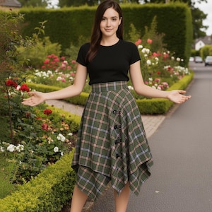 May include: A woman wearing a black short-sleeved top and a green plaid skirt with a unique asymmetrical hemline. The skirt features a button closure on the side. The background includes a garden with flowers and a paved pathway.