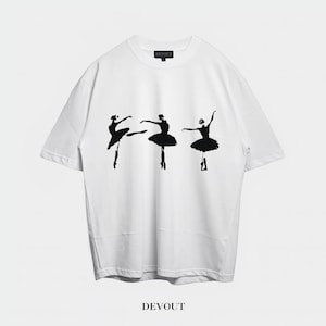 Pode incluir: Camiseta branca com três silhuetas pretas de bailarinas em várias poses. A palavra "DEVOUT" está impressa em preto na parte inferior. A camiseta tem gola redonda e mangas curtas.