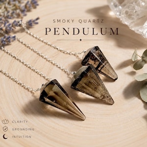 May include: Three smoky quartz pendulums with silver-toned chains. The text reads SMOKY QUARTZ PENDULUM, CLARITY, GROUNDING, and INTUITION. Each crystal is faceted into a pointed cone shape, displaying translucent brown and grey tones.