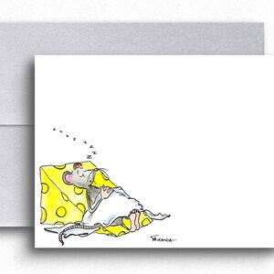 May include: A white greeting card with a watercolor illustration of a sleeping mouse on a yellow cheese wedge. The mouse is covered with a white blanket, and the word "z" is repeated above the mouse. A gray envelope is behind the card.