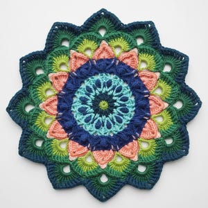 Può includere: Un centrino all'uncinetto fatto a mano e colorato con un motivo floreale circolare. Il centrino presenta anelli concentrici blu, verdi, pesca e turchese. I bordi hanno un motivo smerlato. Questo pezzo decorativo è perfetto per aggiungere un tocco di fascino fatto a mano.