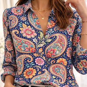 May include: A long-sleeved button-down shirt with a vibrant paisley pattern in shades of blue, pink, orange, and yellow. The shirt has a classic collar and cuffs. The shirt is paired with white pants and a black belt.