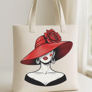 Può includere: Borsa tote in tela color crema con un'illustrazione stilizzata di una donna con un grande cappello rosso con una rosa. La donna ha labbra rosse e orecchini. La borsa ha manici e corpo color crema.