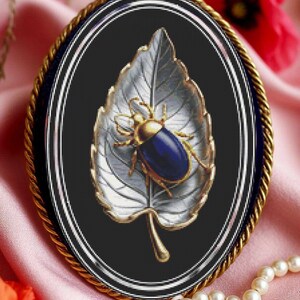 Può includere: Spilla ovale con bordo dorato a forma di corda. La spilla presenta uno scarabeo blu su una foglia bianca con dettagli dorati, su sfondo nero. Probabilmente è un gioiello.