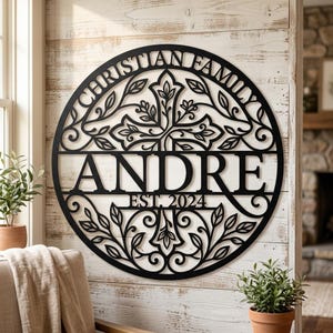 Könnte beinhalten: Ein rundes Wandbild aus schwarzem Metall mit einem filigranen Scherenschnitt-Design eines Kreuzes, umgeben von Blattreben. Der Text "CHRISTIAN FAMILY" ist oben gebogen, der Name "ANDRE" steht in der Mitte und "EST. 2024" darunter.