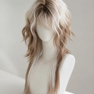 May include: A shoulder-length wig featuring a layered, wavy cut with a mix of light blonde and medium brown tones. The hair has a dark root transition, wispy bangs, and textured ends that fall straight toward the bottom, styled on a mannequin.