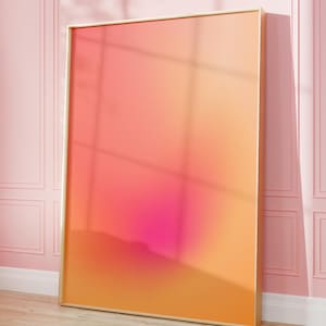 Könnte beinhalten: Ein rechteckiges Wandbild mit einem weichen Farbverlauf in warmen Tönen, der von sanftem Pfirsich und Orange an den Rändern zu einem kräftigen, konzentrierten Magentarosa in der Mitte übergeht, eingefasst in einen dünnen, hellen Rahmen.