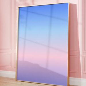May include: A large rectangular wall art piece featuring a smooth vertical gradient that transitions from a bright blue at the top to a soft pink in the middle and a deep purple at the bottom, all encased within a thin, metallic gold frame.