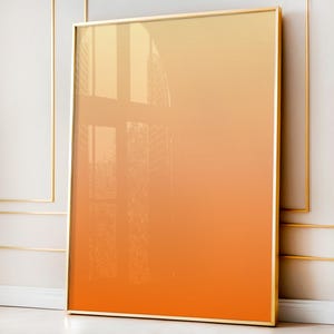 Peut inclure: Impression artistique encadrée avec un dégradé de couleurs chaudes, allant du jaune clair en haut à l'orange foncé en bas. L'œuvre est encadrée dans un cadre doré, ajoutant une touche d'élégance. L'image reflète une fenêtre.
