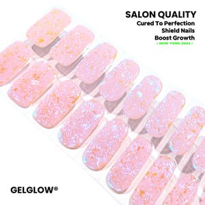 Puede incluir: Una hoja de tiras de gel para uñas en color rosa claro con motas iridiscentes y doradas. El texto dice: SALON QUALITY, Cured To Perfection, Shield Nails, Boost Growth, < NEW YORK 2024 > y GELGLOW. Las tiras están dispuestas en filas.