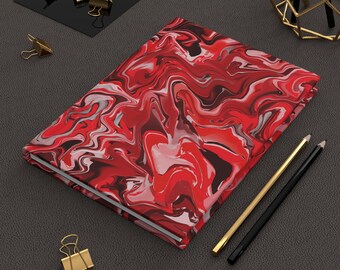 Könnte beinhalten: Ein Hardcover-Notizbuch mit einem lebendigen rot, weißen und schwarzen Marmormuster. Das Notizbuch wird von goldenen und schwarzen Bleistiften und goldenen Büroklammern begleitet. Das Cover hat ein wirbelndes Muster.