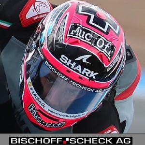 Könnte beinhalten: Ein Motorradhelm mit pinkfarbenen und schwarzen Grafiken sowie verschiedenen Markenaufklebern wie Muc-Off, Shark und e-technik. Das Visier zeigt den Text Bischoff Scheck AG und e-technik-belgien.eu, passend zum Design des Scott Redding Helms.
