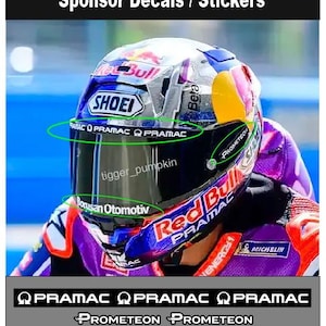 Może przedstawiać: Kask motocyklowy z naklejkami sponsorów na wizjerze. Na wizjerze widnieje napis Pramac, Prometeon oraz Borusan Otomotiv. Kask posiada niebiesko-czerwono-białą kolorystykę z widocznym brandingiem Red Bull oraz Shoei na zewnętrznej powłoce.