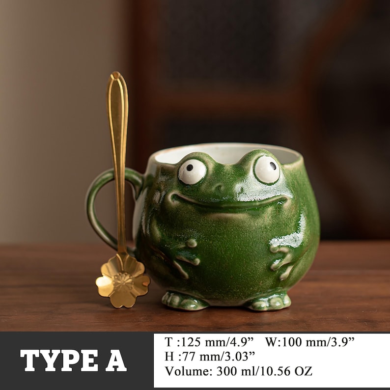 May include: A green ceramic frog-shaped mug with a matching gold-colored spoon. The mug is 4.9 inches wide, 3.9 inches in diameter, and 3.03 inches high. The mug holds 10.56 ounces. The text "TYPE A" is at the bottom.