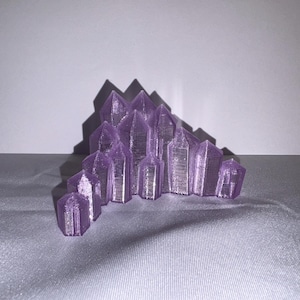 K&ouml;nnte beinhalten: Eine Ansammlung von lila Kristallformationen, m&ouml;glicherweise Amethyst, in einem Halbkreis angeordnet. Die Kristalle haben ein facettiertes Design und sind vor einem neutralen Hintergrund platziert, wodurch ein Spiel von Licht und Schatten entsteht.