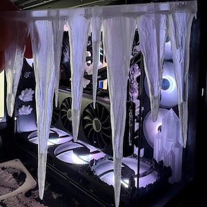 May include: A custom computer case with a winter theme. The case features a series of clear, icicle-shaped decorations hanging from the top. The internal components, including fans and a graphics card, are visible.