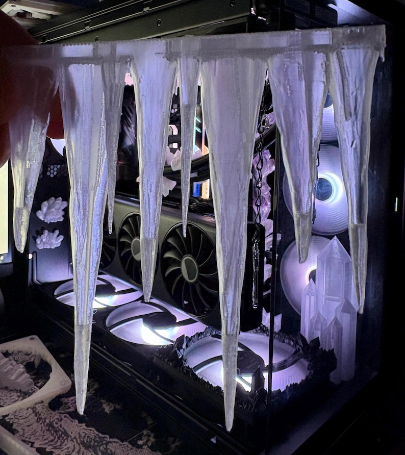 May include: A custom computer case with a winter theme. The case features a series of clear, icicle-shaped decorations hanging from the top. The internal components, including fans and a graphics card, are visible.