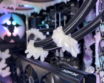 May include: A custom-built computer with a black graphics card and fans. The computer case is decorated with white, crystalline structures around the fans and cooling system. The fans have colorful LED lights.