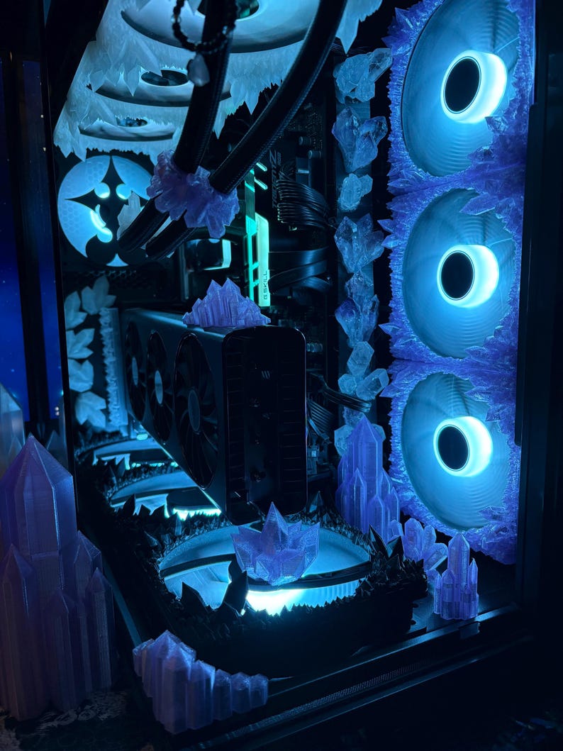 K&ouml;nnte beinhalten: Ein individuell gestaltetes Computergeh&auml;use mit einem blau-wei&szlig;en Eisthema. Es verf&uuml;gt &uuml;ber blaue LED-L&uuml;fter, dekorative Eiskristallakzente und einen leuchtenden Innenraum. Die Gesamt&auml;sthetik ist ein cooler, futuristischer Look.