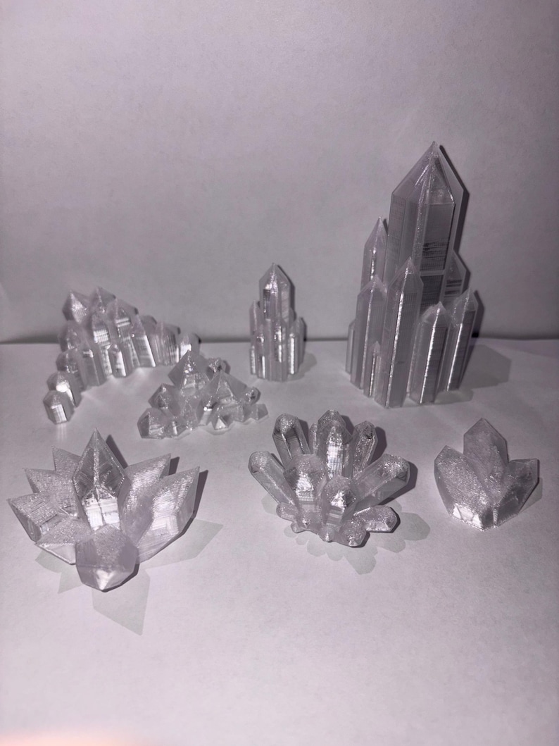 May include: A collection of clear, crystalline structures in various shapes and sizes. The objects resemble clusters and formations of crystals, with sharp edges and pointed tips. The translucent material allows light to pass through, creating a shimmering effect.