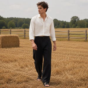 May include: A long-sleeved, off-white button-down shirt with a chest pocket and a classic collar, paired with loose-fitting black trousers featuring a pleated waist and a simple black belt. The outfit is completed with black open-toe leather sandals.