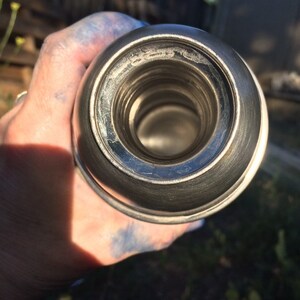 May include: Close-up of the inside of a silver thermos with a shiny, reflective surface.