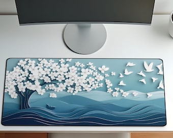 May include: A white desk with a computer monitor, a silver desk lamp, and a decorative mousepad. The mousepad features a blue and white design of a tree, birds, and waves. The desk is set up for work.