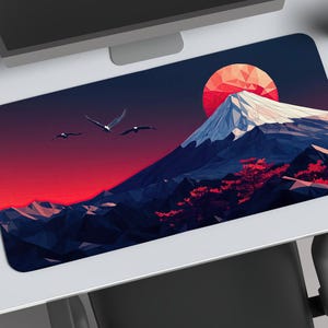 May include: Rectangular mousepad featuring a low-poly illustration of a snow-capped mountain with a red sun and flying birds against a red and blue sky. The mousepad is on a white desk.