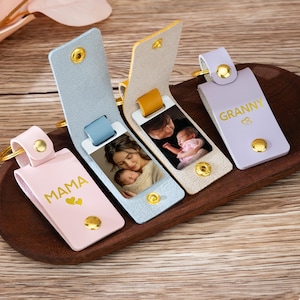 May include: Four personalized leather keychains in pink, blue, and yellow, each with a gold-colored snap closure and a gold-colored keyring. The keychains feature photos and the words "MAMA" and "GRANNY".