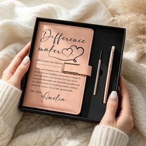 Può includere: Un taccuino color pesca chiaro con chiusura magnetica, caratterizzato dal testo "Difference maker" e da una definizione stampata in inchiostro nero, personalizzato con il nome "Amelia". Il set include una penna metallica abbinata e un ricambio.