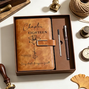 May include: A tan leather-like journal set in a brown box, featuring the text Chapter EIGHTEEN, a flower illustration, the name Sophia, and the phrase The Hopeful Soul. Every chapter brings new growth. Includes a matching pen and ink refill.