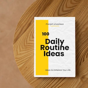 Op de afbeelding: Een boek getiteld "100 Daily Routine Ideas" door Pranjali Srivastava. De omslag heeft een witte achtergrond met een verticale gele streep. De titel staat in grote, vette zwarte letters. Het boek ligt op een houten oppervlak.