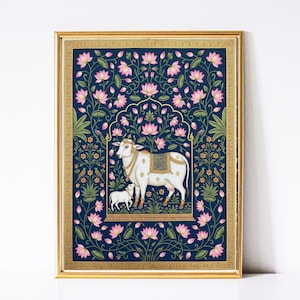 Puede incluir: Una obra de arte enmarcada que presenta una vaca y un ternero blancos, adornados con detalles dorados, sobre un fondo azul marino lleno de flores de loto rosas y follaje verde. La obra está encerrada en un marco dorado.