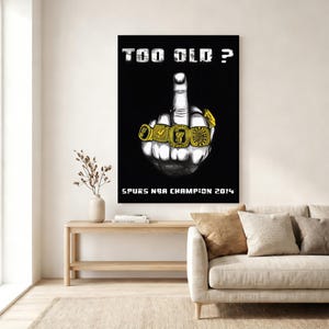 May include: A black poster featuring a white illustration of a hand making a middle finger gesture, with four gold championship rings on the fingers. The text reads "TOO OLD ?" at the top and "SPURS NBA CHAMPION 2014" at the bottom in white.
