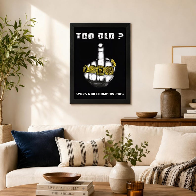 May include: A framed black poster featuring a white illustration of a hand with an extended middle finger wearing gold championship rings. The text reads "TOO OLD ?" at the top and "SPURS NBA CHAMPION 2014" at the bottom in white font.