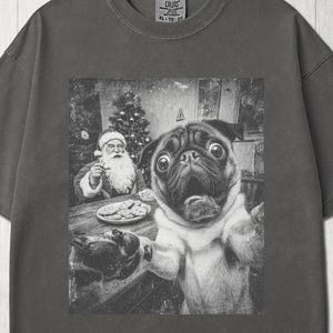 Könnte beinhalten: Ein anthrazitfarbenes Kurzarm-T-Shirt mit einem schwarz-weißen Grafikdruck eines Mopses, der im Vordergrund ein Selfie macht, während im Hintergrund der Weihnachtsmann an einem Tisch mit Keksen und einem geschmückten Weihnachtsbaum sitzt.
