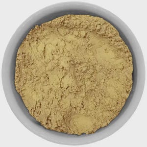 May include: A top-down view of a white ceramic bowl filled with a light brown, finely ground powder. The powder has a slightly textured appearance, and the bowl is set against a plain white background.