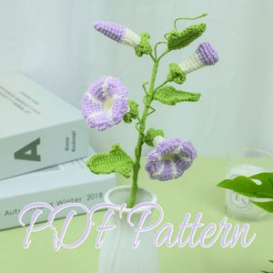 May include: A handmade crochet flower arrangement featuring purple and white morning glories with green leaves and stems. The flowers are displayed in a white vase. The text "PDF Pattern" is overlaid on the image.