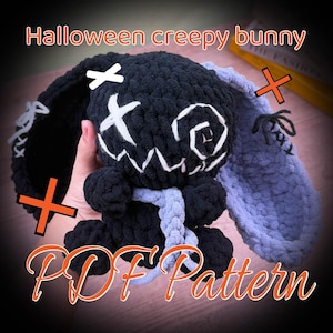 May include: A handmade black crochet bunny with white stitched facial features and a light blue scarf. The bunny has long ears, one black and one light blue. The text "Halloween creepy bunny" and "PDF Pattern" are displayed in orange.