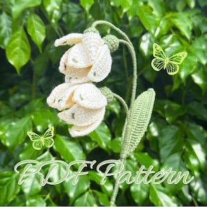 Op de afbeelding: Crèmekleurige gehaakte bloemen met groene accenten en een groene stengel. De bloemen hebben een delicate, getextureerde uitstraling. De afbeelding bevat de tekst "PDF Pattern" in cursief en twee groene vlinderillustraties.
