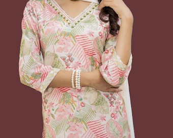 May include: A floral print kurta set in white, pink, and green. The long-sleeved top has a V-neck with embroidered detailing. A matching scarf is draped over the shoulders. A pearl bracelet and ring are also visible.