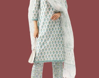 May include: A white and blue floral print kurta set. The set includes a long-sleeved tunic, matching pants, and a sheer scarf. The floral pattern is in shades of blue and green. The outfit is paired with white sandals and a white purse.