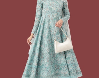 May include: A light blue A-line dress featuring a white floral pattern, long sleeves, and a matching scarf draped over the shoulders. The dress is paired with matching patterned trousers and a solid white handbag with a curved top handle.