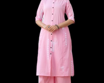 May include: A light pink knee-length tunic featuring a mandarin collar, a front button placket with dark buttons, and three-quarter length sleeves. The garment is decorated with a subtle white geometric triangle pattern and paired with matching wide-leg pants.