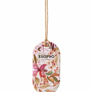 以下が含まれることがあります： ピンク、赤、緑の色合いの花柄が施された楕円形のタグ。 タグには「EUORPHO」の文字と「ENCOUNTER LOVE」のテキストが印刷されています。 上部には天然の麻ひもが取り付けられています。